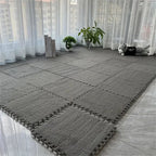 Gray interlocking foam mats on a floor with white curtains in the background