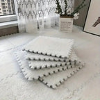 Stack of white foam mats on a light-colored floor with a decorative plant in the background.