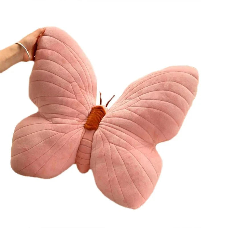 Pink butterfly-shaped pillow held by a hand on a white background