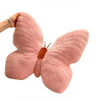 Pink butterfly-shaped pillow held by a hand on a white background