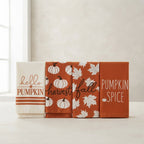 Four autumn-themed fabric towels or napkins displayed side by side on a light surface. The set includes designs with 'hello PUMPKIN', 'harvest fall', white pumpkins on an orange background, and 'PUMPKIN SPICE' text on an orange background.