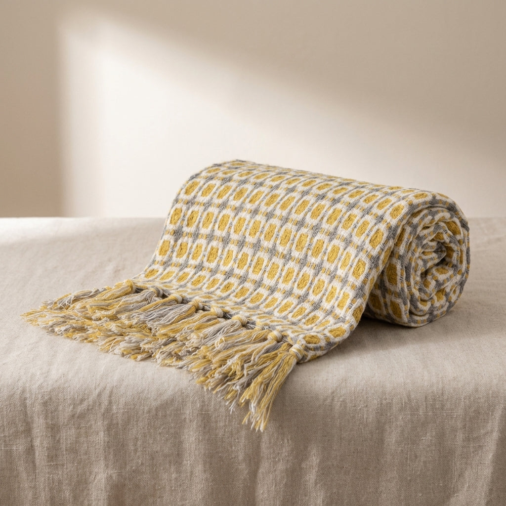 Rolled-up checkered blanket with tassels on a beige surface