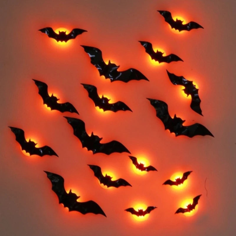 A set of black plastic bat wall decals or decorations arranged on a plain background, each glowing with a warm orange light from within.