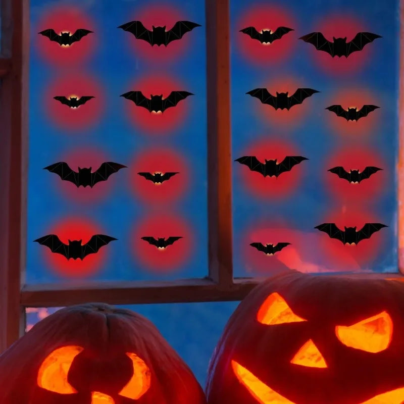 Halloween window decoration set featuring black bat cutouts that glow with red light, displayed on a window pane above carved jack-o'-lantern pumpkins.