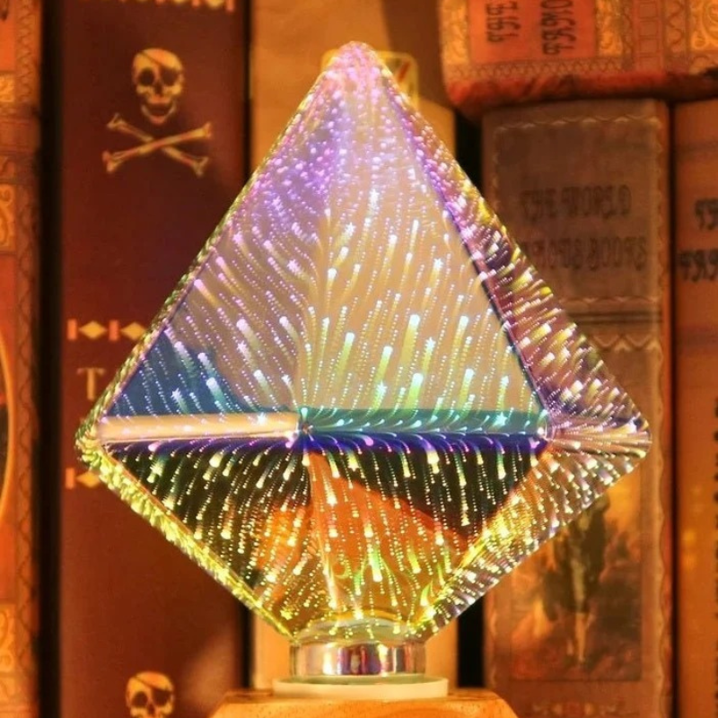 A clear diamond-shaped crystal or glass lamp with a glowing internal light pattern, set on a wooden base in front of a background of old books.