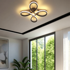 Modern ceiling light fixture in a room with a large window and plant