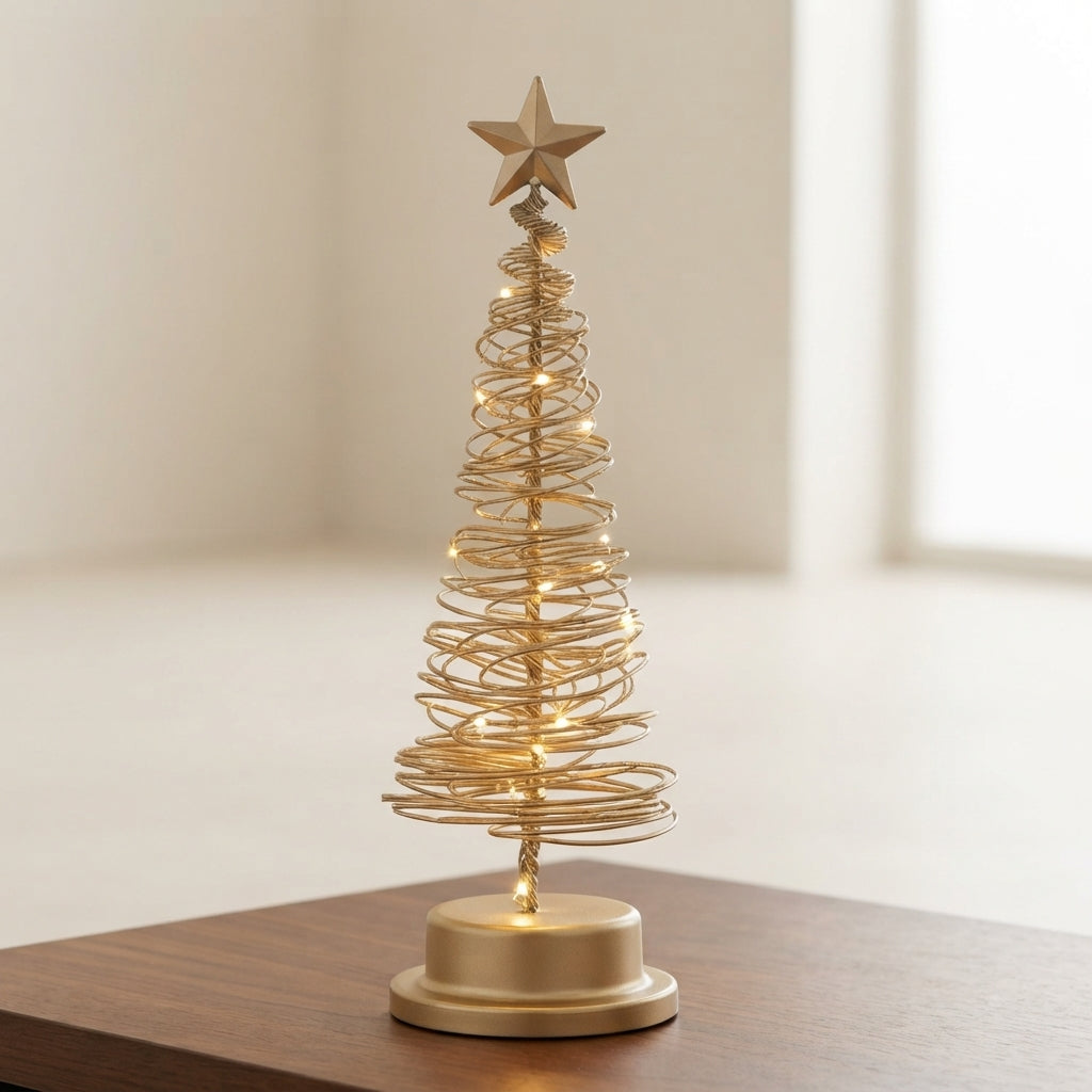 A small gold wire spiral Christmas tree with warm white string lights and a gold star topper, displayed on a wooden surface in a softly lit indoor setting.