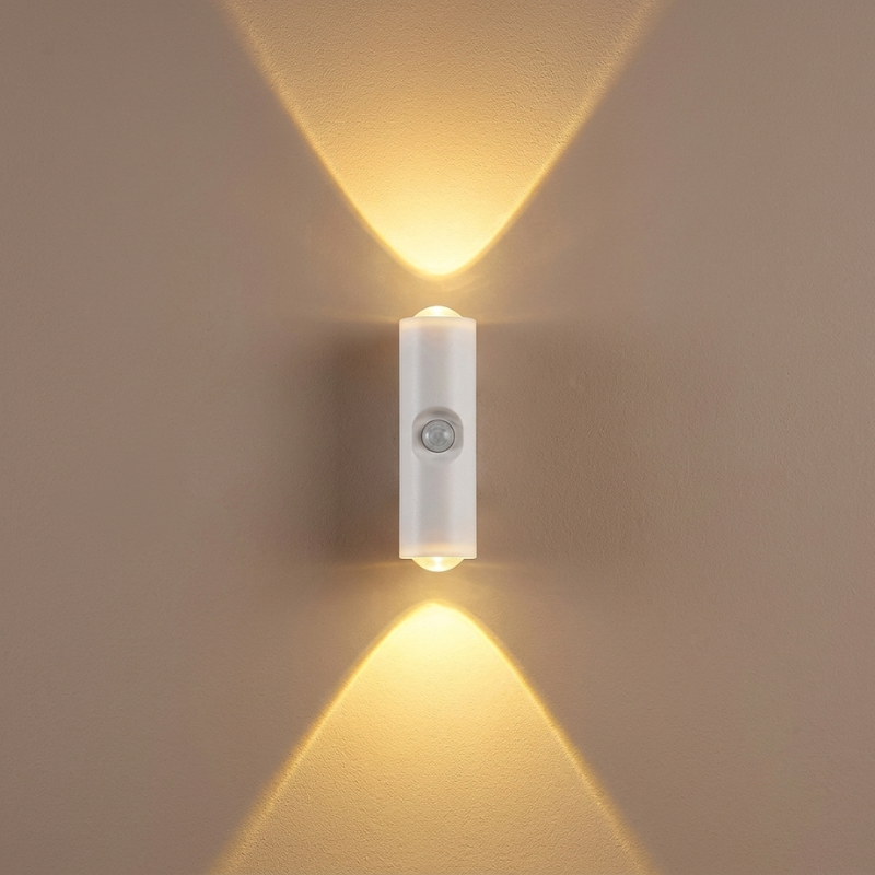 Wall-mounted light fixture casting two beams of light on a beige wall.