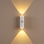 Wall-mounted light fixture casting two beams of light on a beige wall.