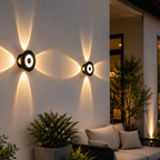 Outdoor wall lights on a building exterior with a couch and plants in the foreground.
