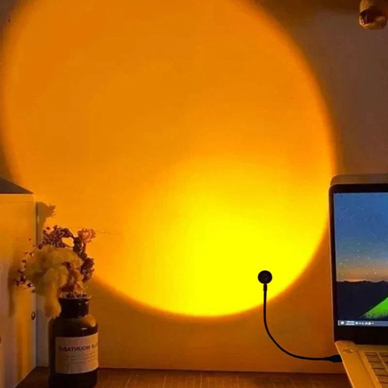 Yellow light projection on a wall with a bottle and laptop in the foreground