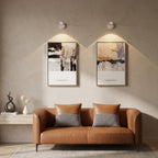 Brown leather sofa with checkered cushions in a room with abstract wall art and lighting fixtures.