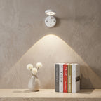 Wall-mounted light fixture casting a warm glow on a shelf with books and a vase.