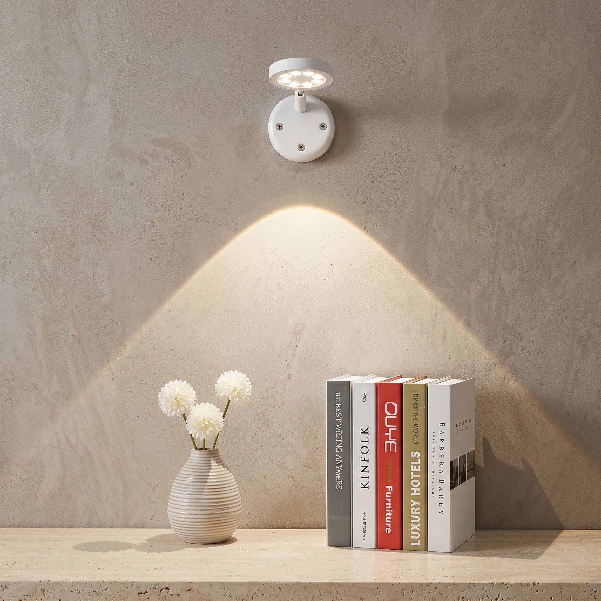 Wall-mounted light fixture casting a warm glow on a shelf with books and a vase.