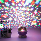 Colorful starry night light projector on a table with a 'Design Hotels Yearbook 09' in the background.