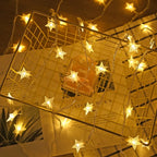 Warm white star-shaped LED fairy string lights draped over a gold wire basket on top of books, creating a cozy golden ambiance.