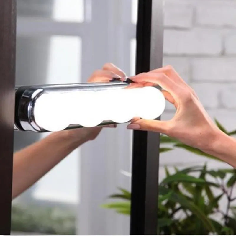 Person holding a cylindrical light fixture against a blurred indoor background