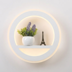 Round wall light fixture with a plant and small Eiffel Tower model on a neutral background