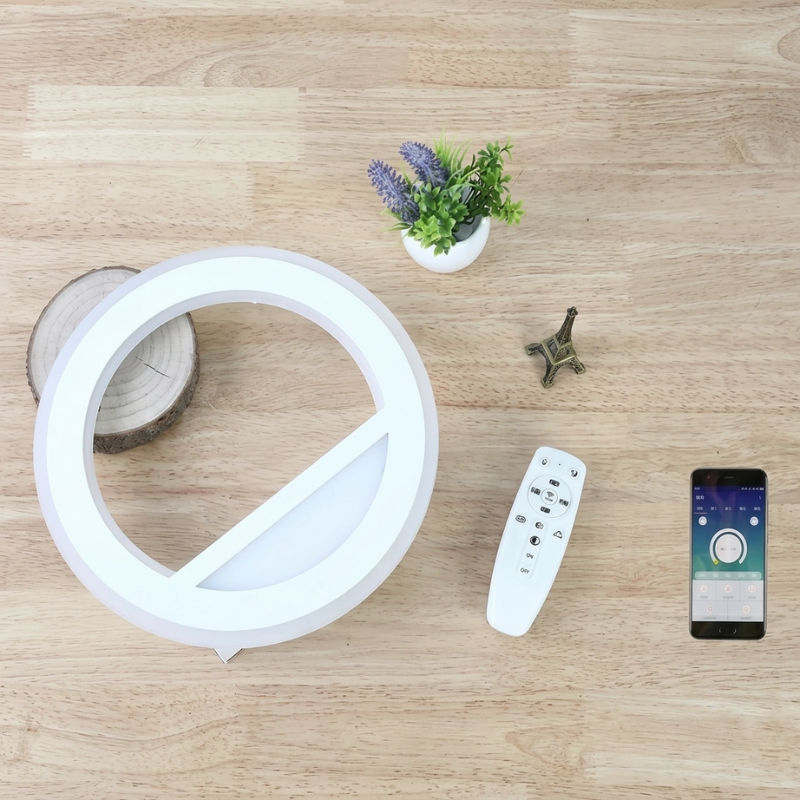 Round LED light fixture with remote control and smartphone app on a wooden surface