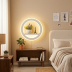 Modern bedroom with a round illuminated wall light fixture, books, and decorative items.
