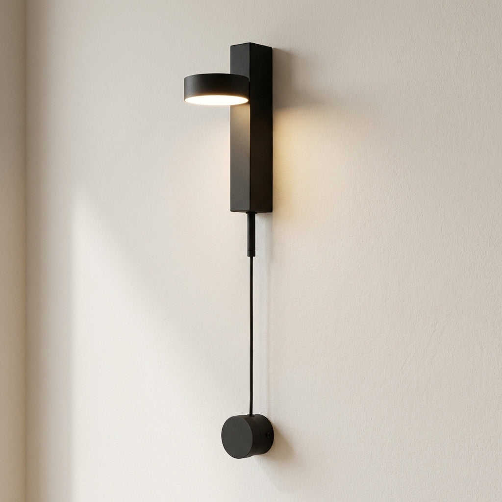 Modern black wall lamp with a cable extension on a light beige wall.
