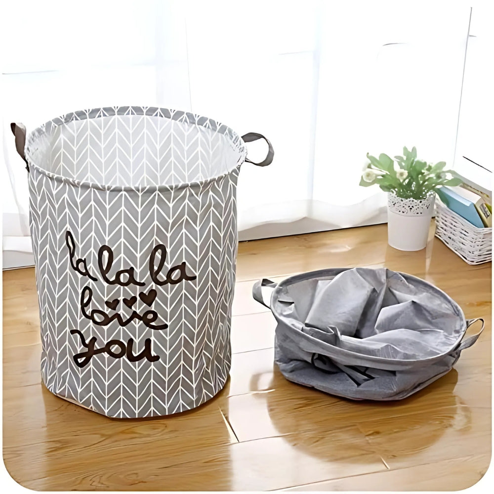 Gray laundry basket with 'la la la love you' text on a wooden floor.
