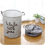 Gray laundry basket with 'la la la love you' text on a wooden floor.