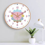 Colorful wall clock on a white wall with a plant and lamp in the background