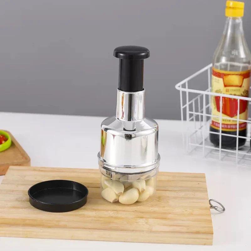 Garlic press on a wooden cutting board with garlic cloves inside, on a kitchen counter.