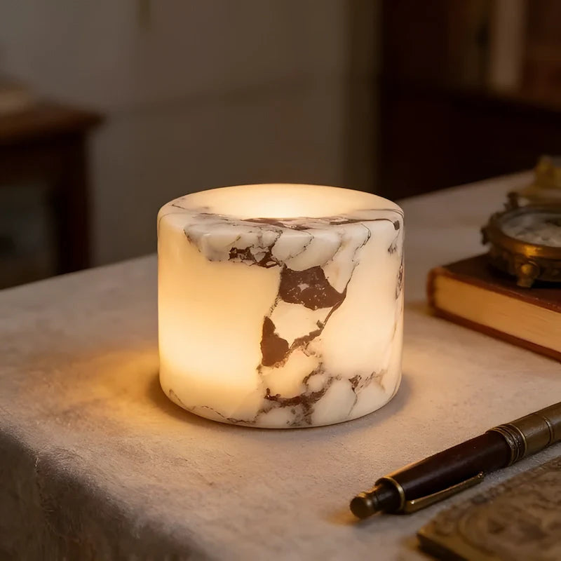 Marble-patterned candle on a surface with a pen and book in the background