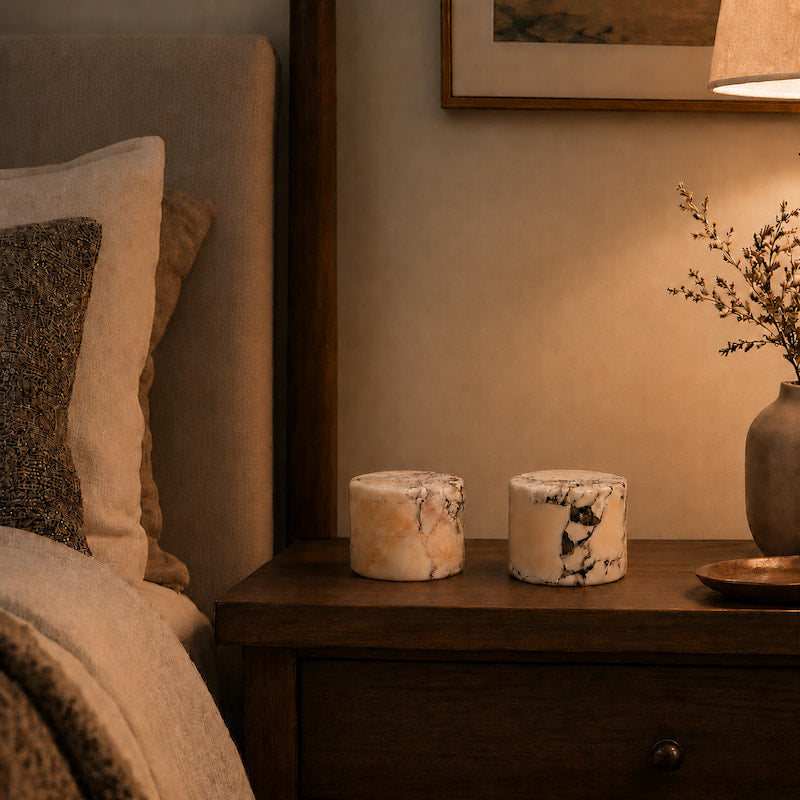 Napkin holder on a wooden nightstand next to a bed with pillows.