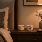 Napkin holder on a wooden nightstand next to a bed with pillows.
