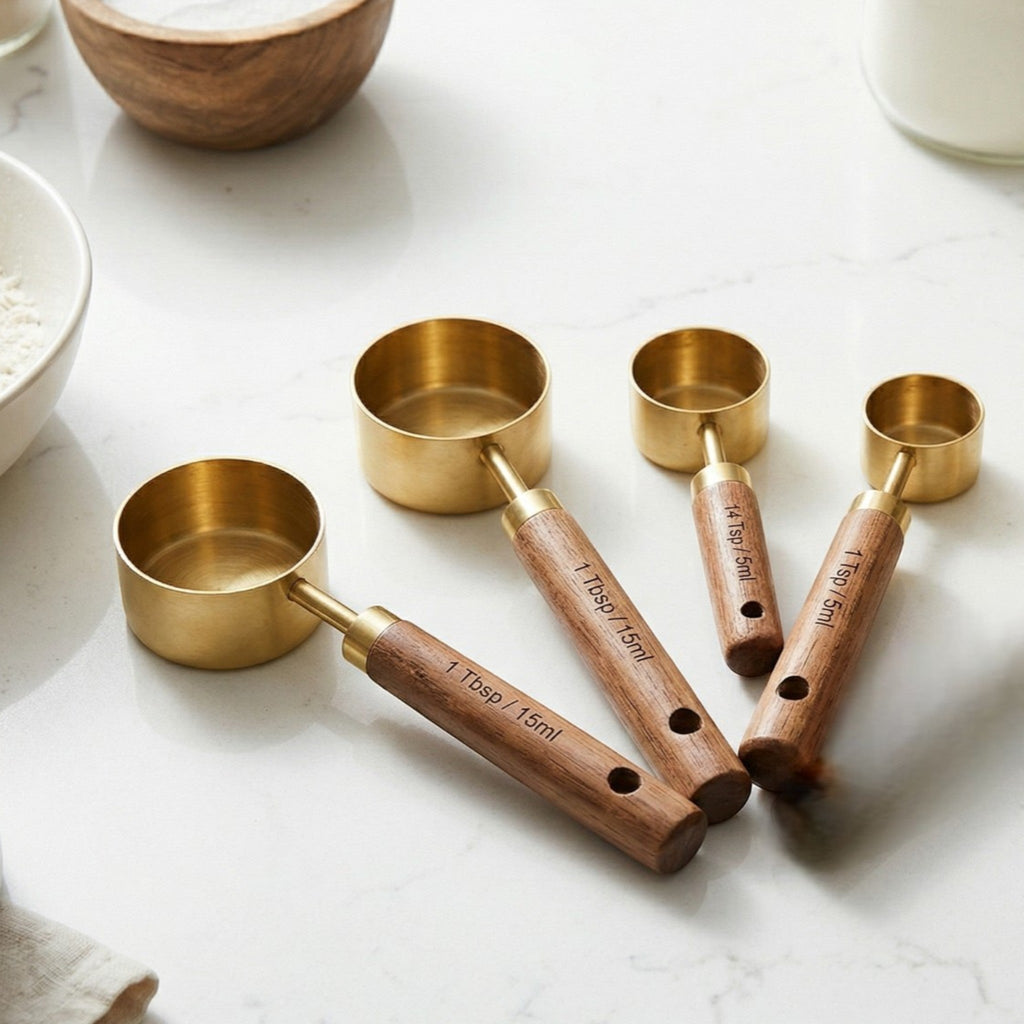 Set of brass measuring cups with wooden handles on a marble surface