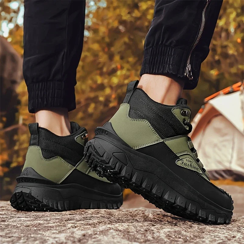 Black and green hiking boots worn by a person standing on a rock with a blurred natural background