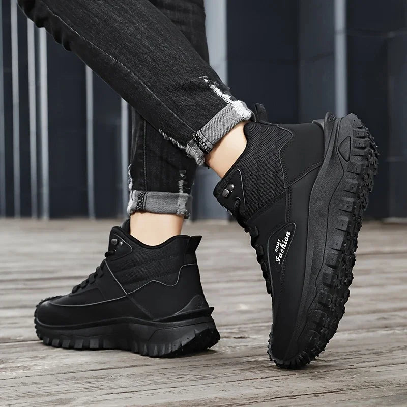 Black boots worn with rolled-up jeans on a wooden floor.