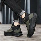 Person wearing green and black hiking boots on a wooden floor.