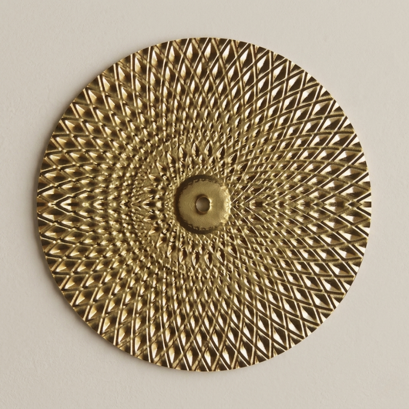 Decorative gold circular plate with intricate patterns on a beige background