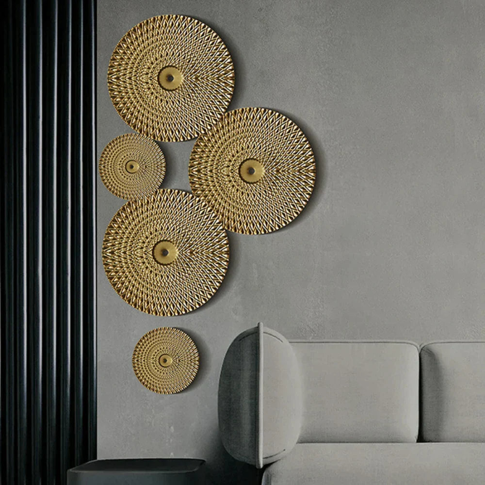 Decorative gold circular wall art pieces on a gray wall with a gray sofa.