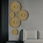 Decorative gold circular wall art pieces on a gray wall with a gray sofa.