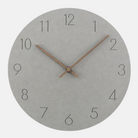 Round wall clock with concrete-like finish and bronze hands on a white background