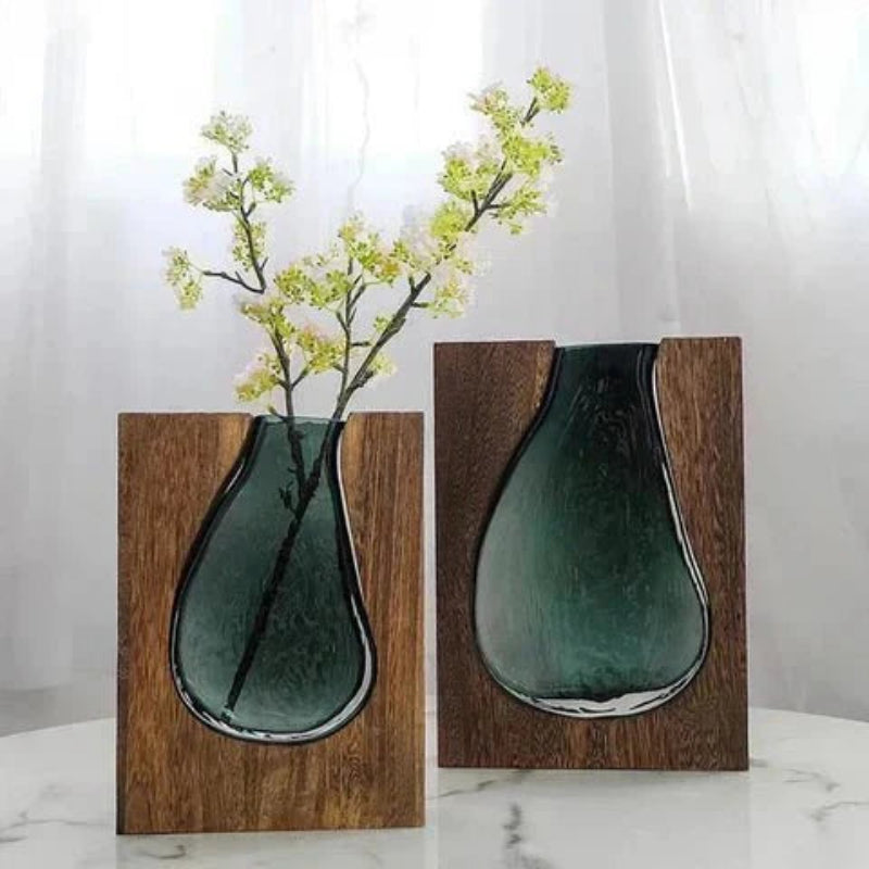 Two teal glass vases with wooden bases on a white background