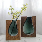 Two teal glass vases with wooden bases on a white background