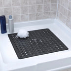 Black perforated bath mat on a bathtub with shower products in the background