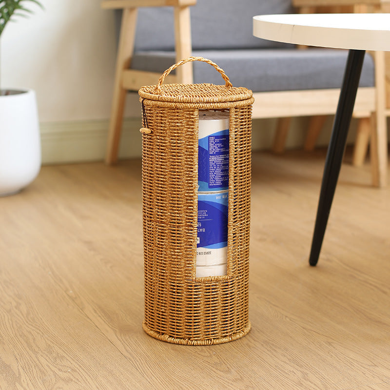 Wicker basket with a handle containing toilet paper on a wooden floor.