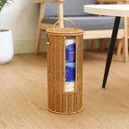 Wicker basket with a handle containing toilet paper on a wooden floor.