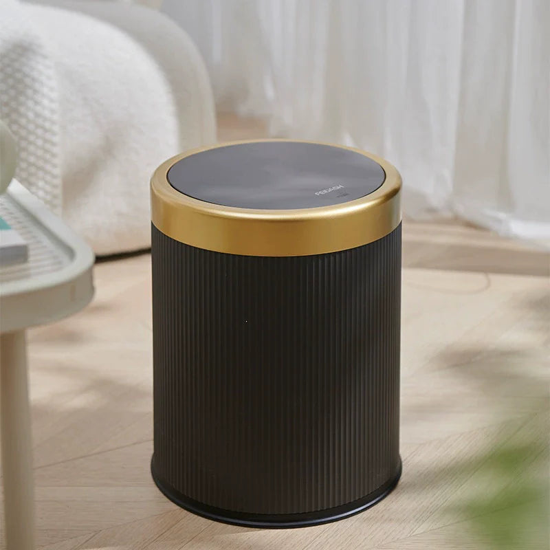 Black trash bin with gold lid on a wooden floor