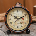 Vintage-style clock with floral designs on a wooden surface