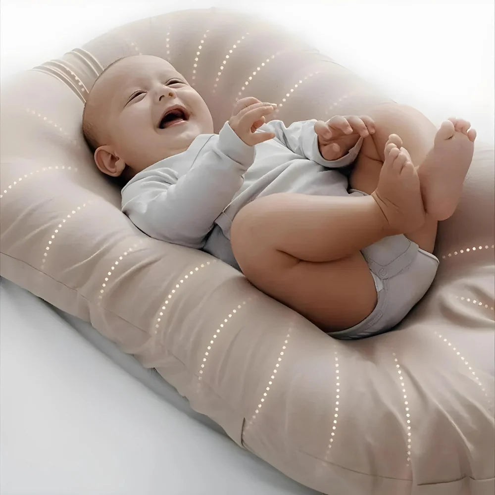 Baby lying on a beige cushion with a soft focus background