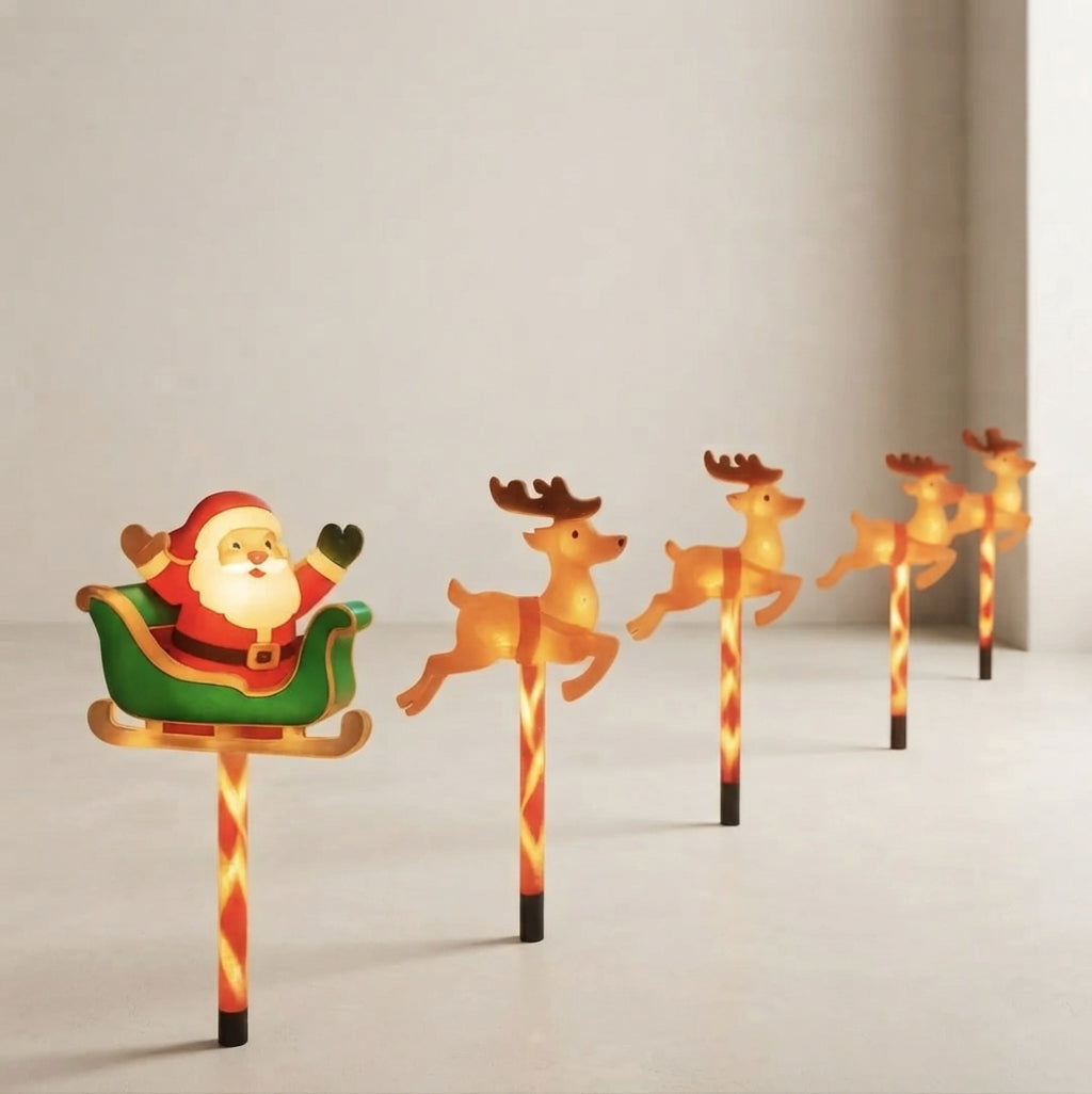 A set of festive outdoor Christmas ground lights featuring Santa Claus in a green sleigh pulled by four glowing reindeer, mounted on red-and-white striped poles.