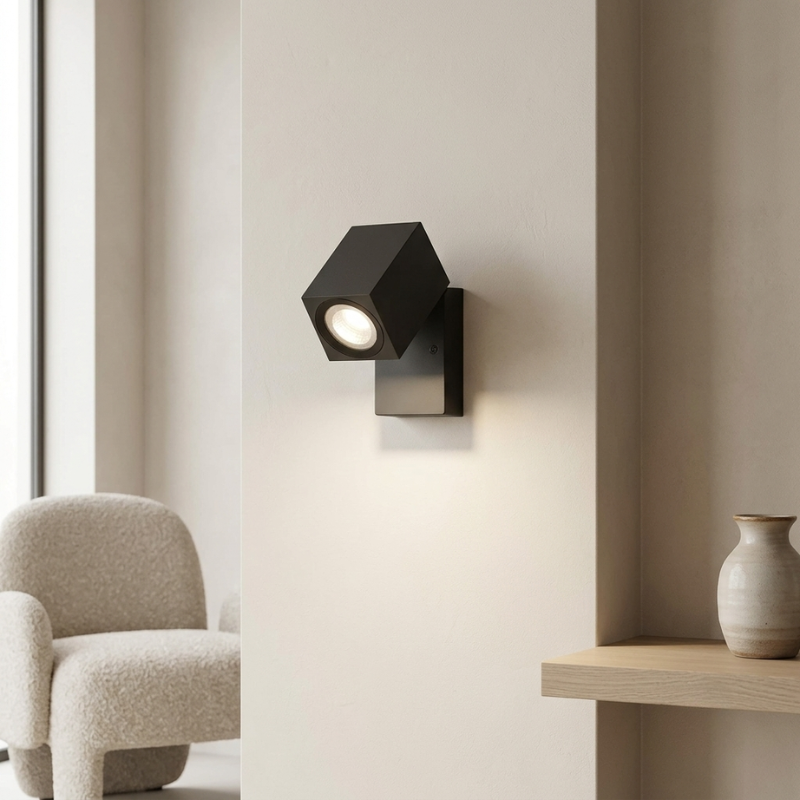 Modern wall light fixture on a neutral wall with a chair and vase in the background